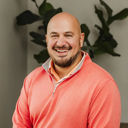 Headshot of Aaron Schwartz, a middle-aged Caucasian man with a beard, smiling warmly and wearing a salmon-colored shirt.